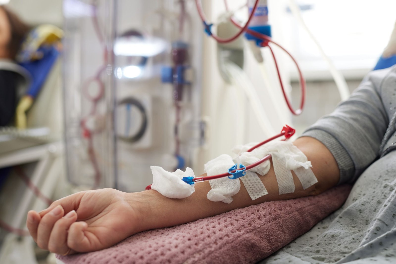 A woman lying in a hospital bed with an IV drip attached, looking weak and resting.